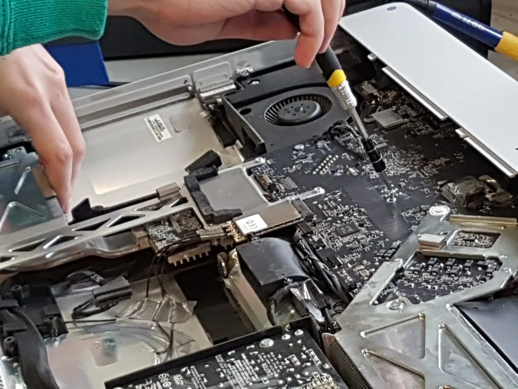 A technician working on the inside of a laptop at the Surrey Computer Centre workshop